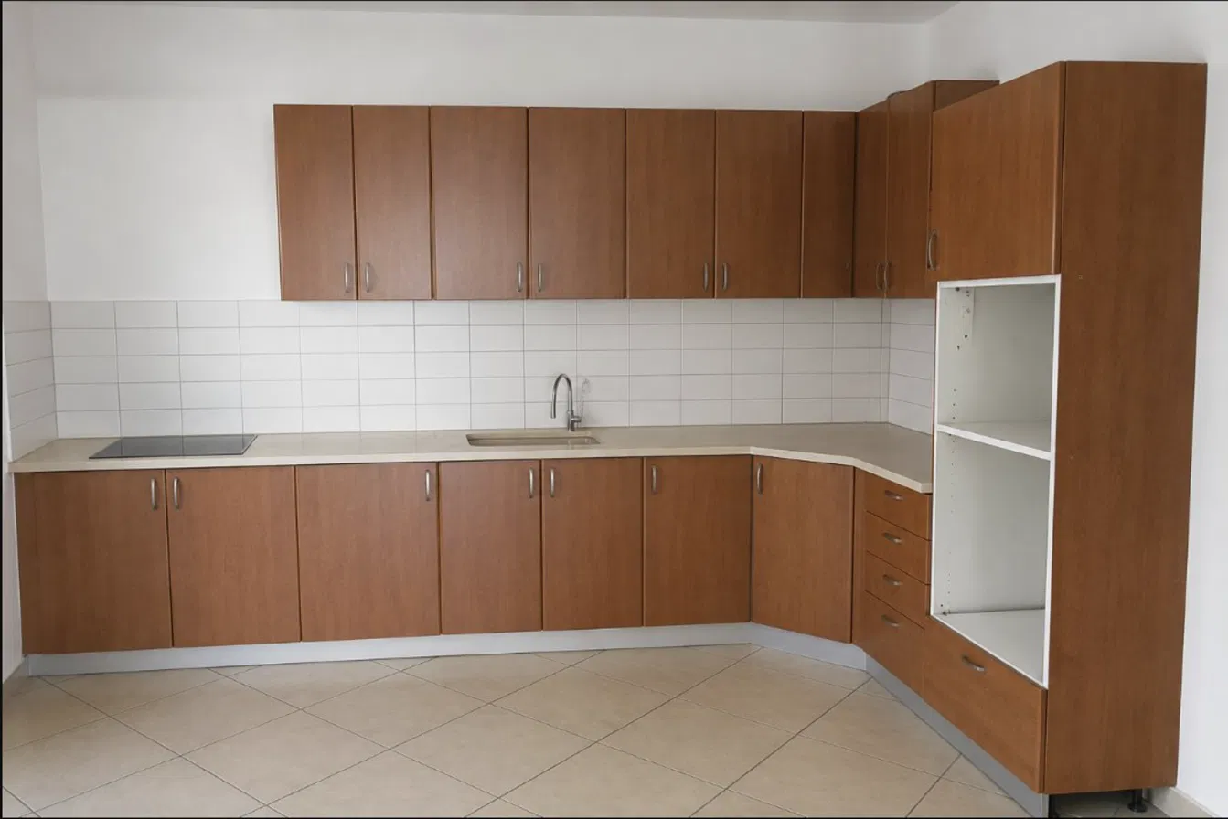 מטבח בצורת L עם ארונות בצבע חום ישן לפני חידוש עם טפט - דוגמה לחישוב מחיר