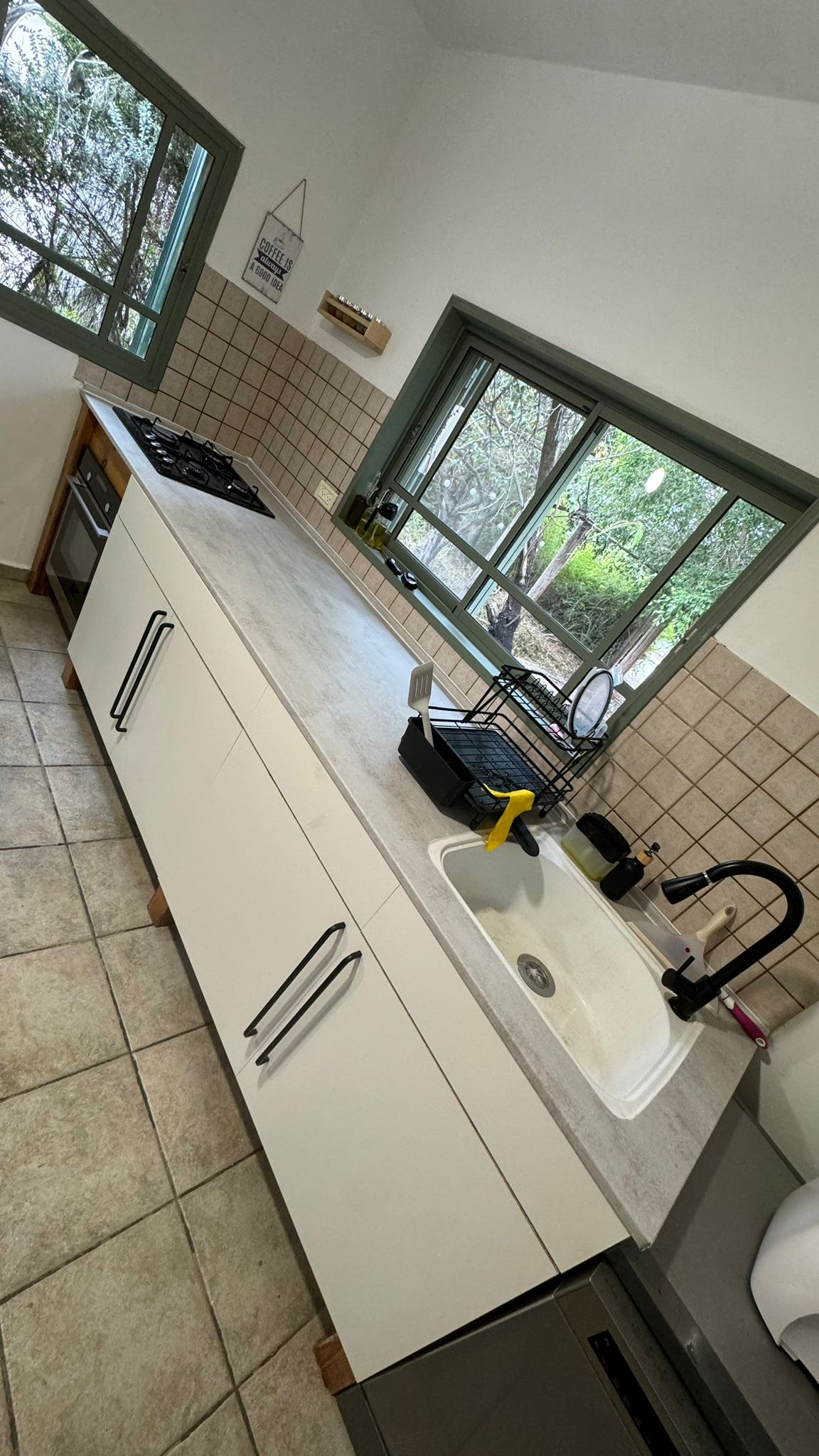 מטבח עם ארונות לבנים ומשטח דמוי שיש אחרי התקנה עצמית